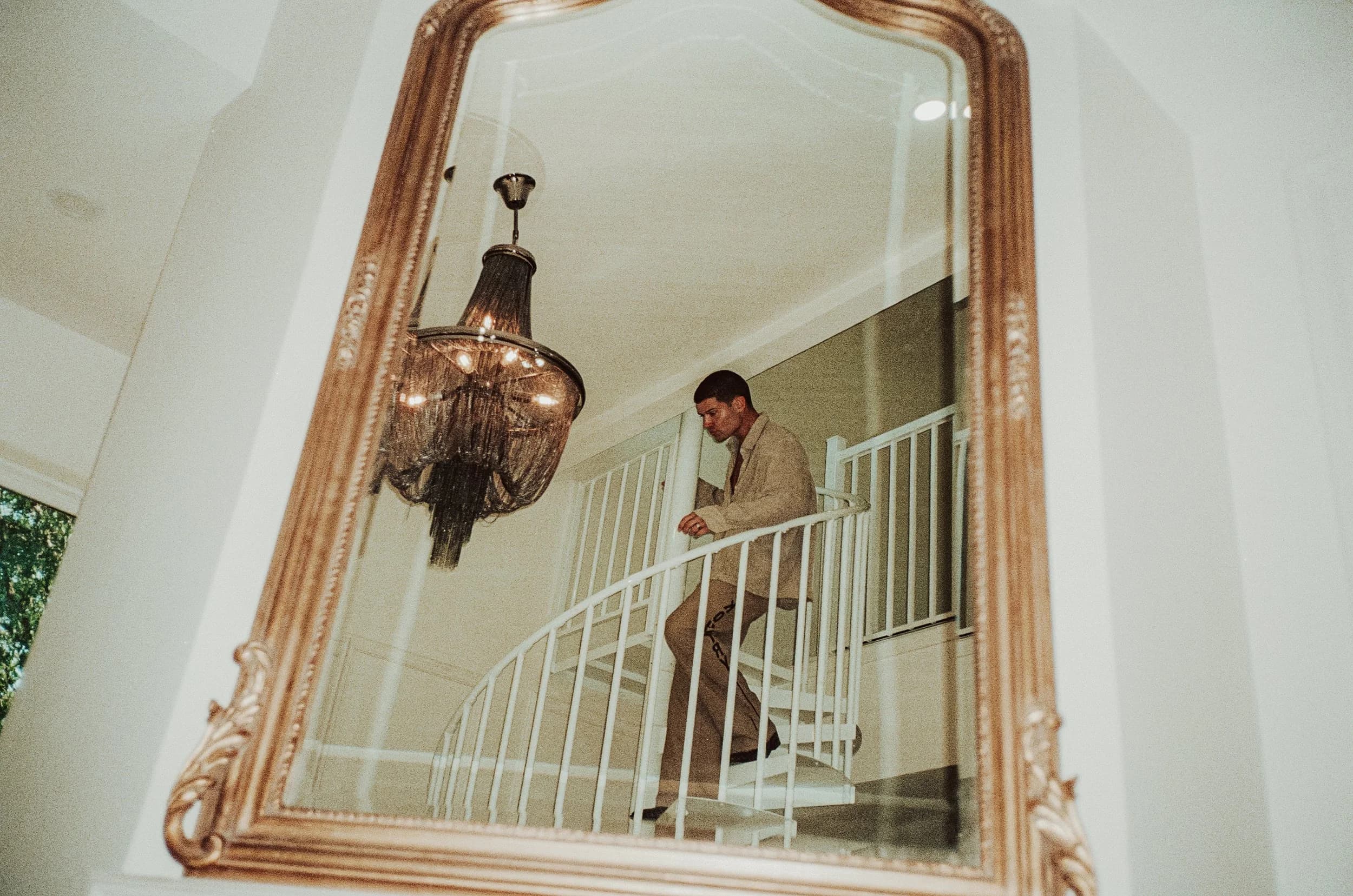 A spiral staircase and chandelier reflected in a gilt mirror inside a residence at The Clarksville