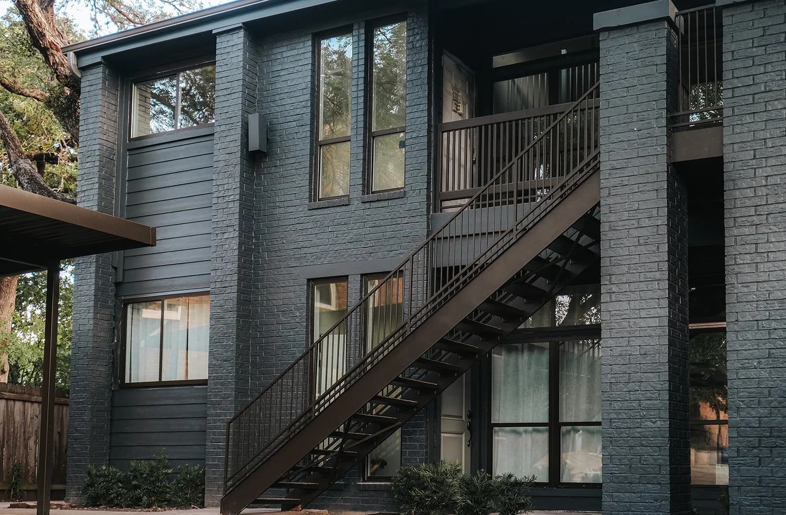 Exterior of The Clarksville, dark-brick facade with black metal stairs under a tree canopy
